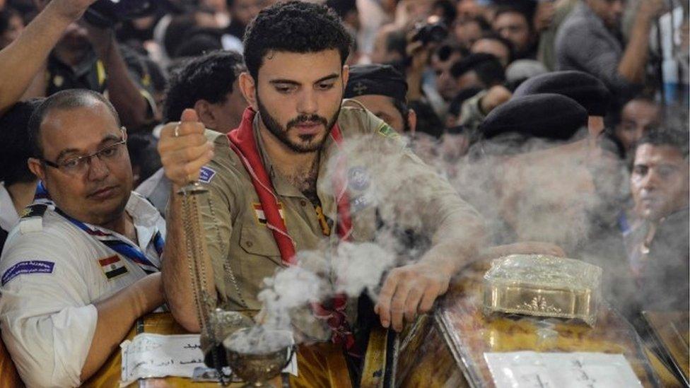 A man burns incense by a coffin as relatives of killed Coptic Christians gather during a funeral in the north Minya town of Maghagha (26 May 2017)