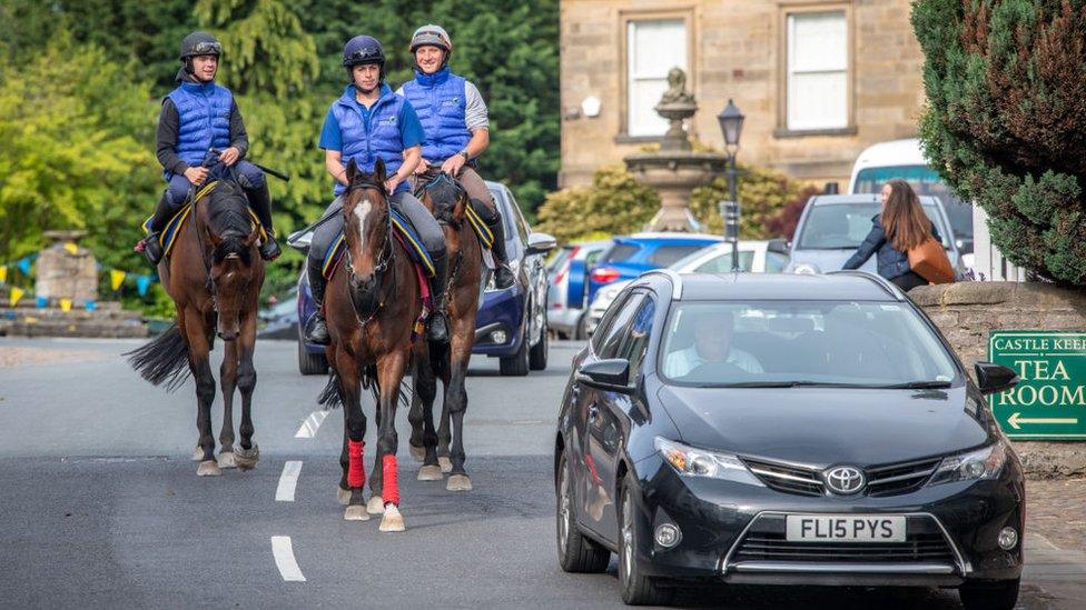 Middleham, England - A group of equestrians ride along a small village street, Yorkshire, UK.