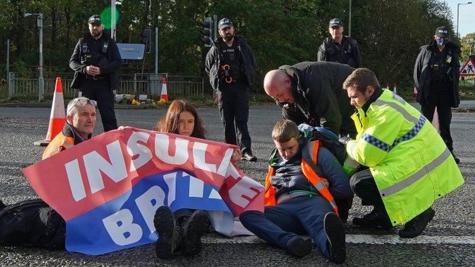 Police officers try to move protesters from the road