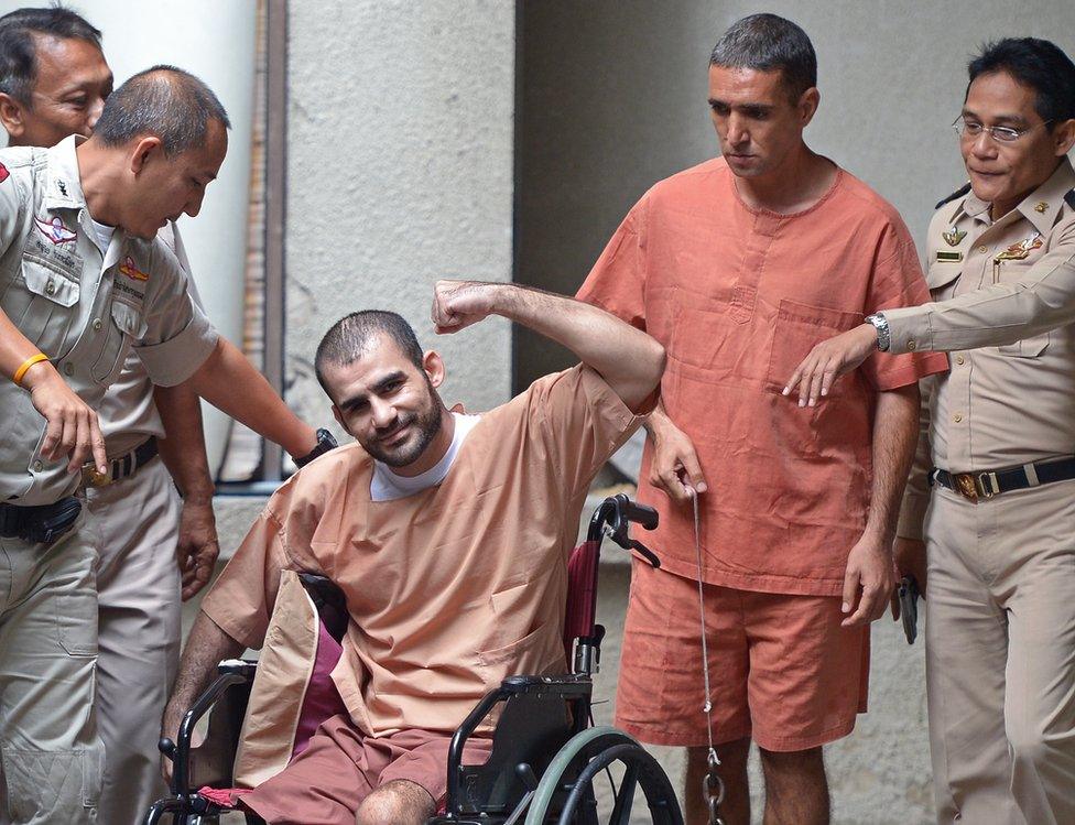 Saeid Moradi, 29, (C), an Iranian suspected of involvement in the February 2012 bomb blasts in Bangkok, gestures to the media next to Mohammad Khazaei (2nd R), 43, during an apprearance at the southern criminal court in Bangkok on August 22, 2013.