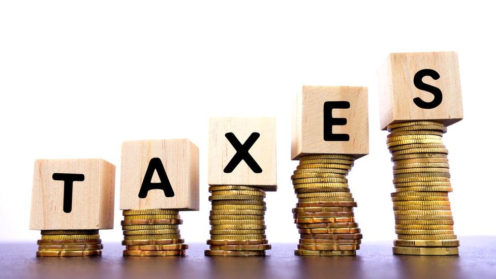 Taxes Word on wood block on top of coins stack - stock photo