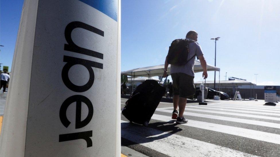 A person with suitcase by an Uber sign