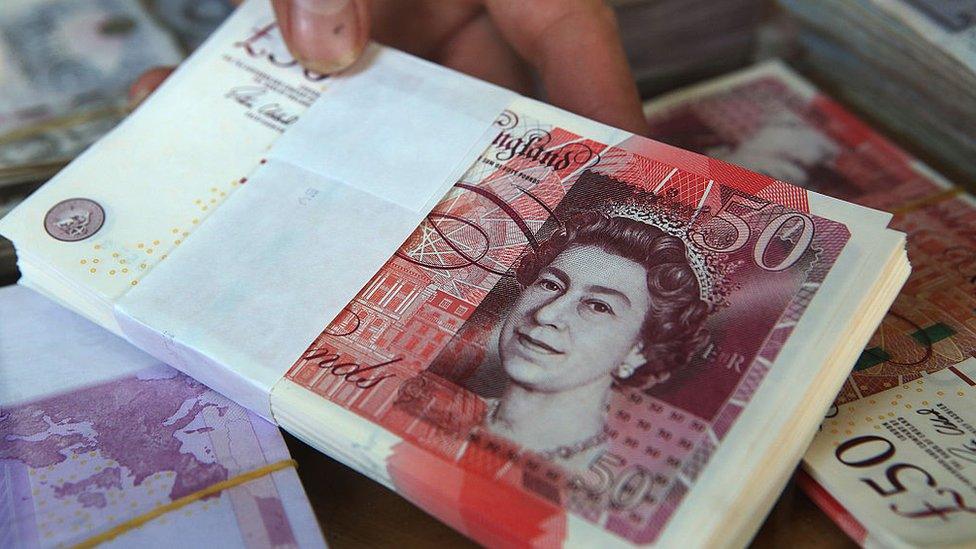 A vendor holds British pound banknotes