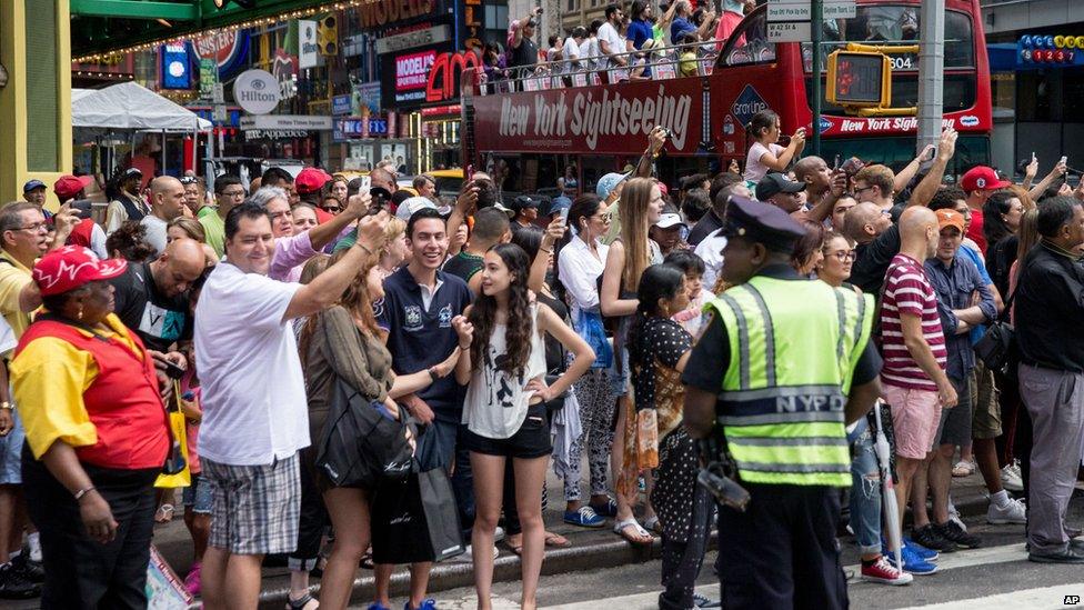 A crowd gathers along 8th Avenue in New York, Saturday, July 18, 2015,