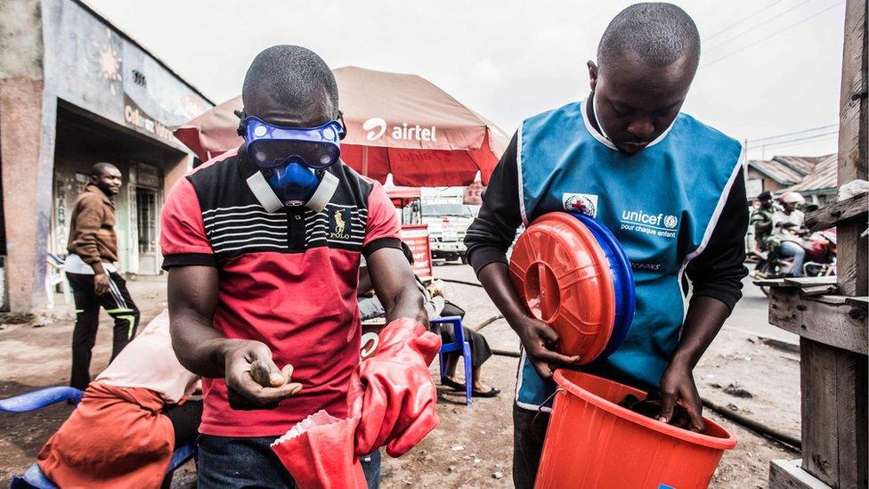 Health workers wear protective gear to mix water and chlorine in Goma