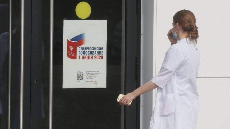 A medical specialist approaches the front door of a hospital complex with a pasted poster