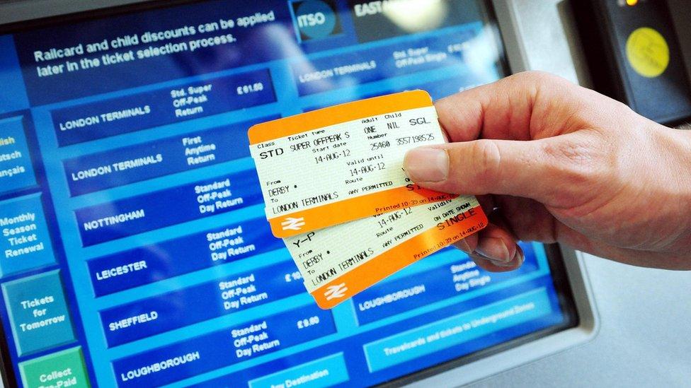 File photo showing a man holding up train tickets in front of a ticket terminal.