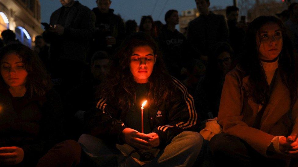 Protesters hold candles during a demonstration in front of Hellenic Train headquarters