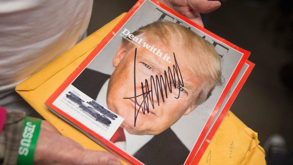 A woman holds an copy of Time magazine that Donald Trump has signed.