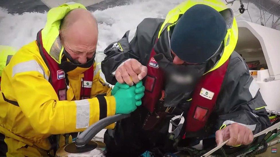 Two men fighting strong waves at sea