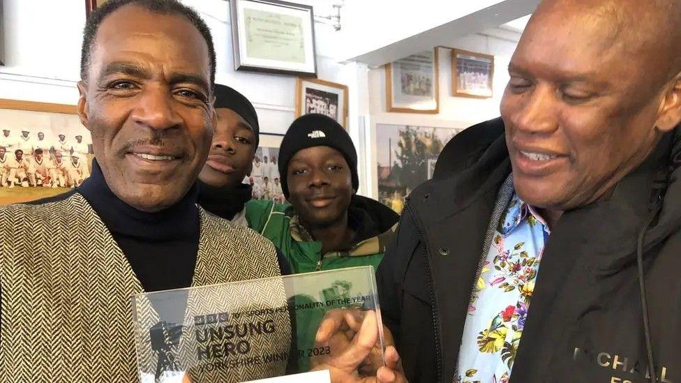 Des Smith holds his BBC Sports Personality of the Year Unsung Hero Award, alongside cricketer Devon Malcolm.