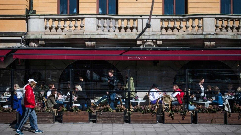 People enjoy the spring weather as they sit at a restaurant in Stockholm on April 15, 2020,