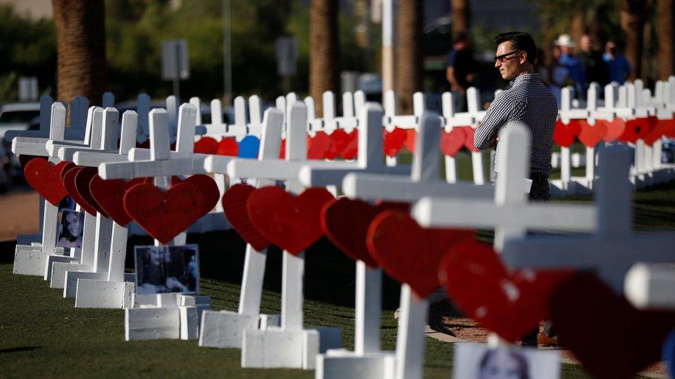 A man looks at the 58 white crosses set up for the victims of the Route 91 music festival mass shooting in Las Vegas