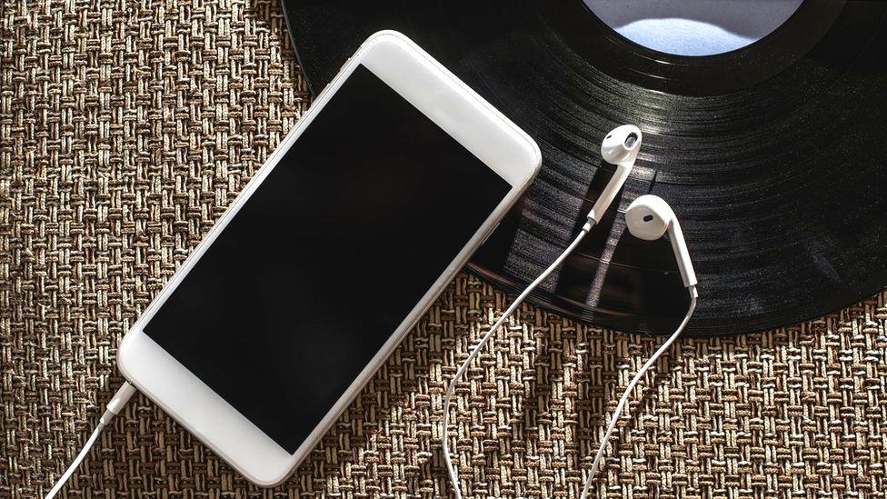 A mobile telephone and a vinyl record on a table top