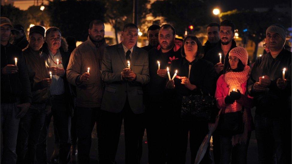 Tunisian Nidaa Tounes party members hold candles during a vigil in Tunis in memory of the victims of a bomb blast on a bus transporting Tunisia's presidential guard