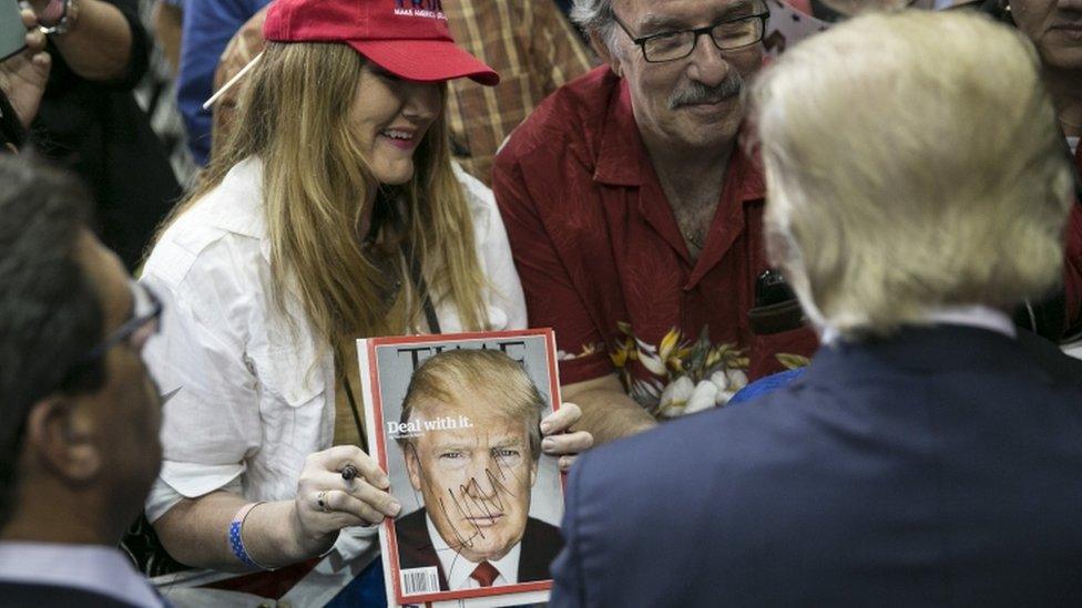 US Republican presidential candidate Donald Trump looks at an freshly-autographed copy of his Time Magazine cover after a campaign rally at the American Airlines Center in Dallas