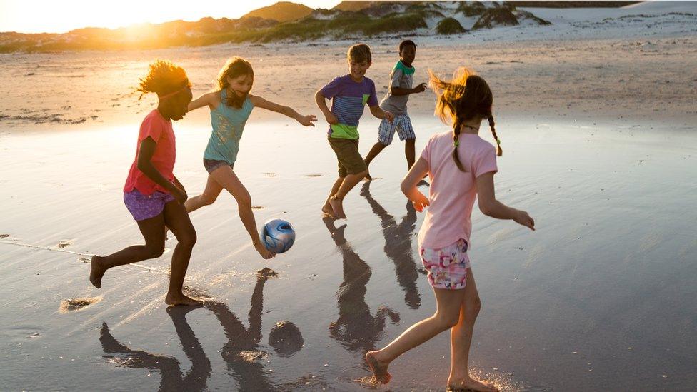 Children playing football on the beach