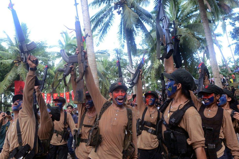 A picture made available on 29 December 2016 shows members of the NPA waving their guns during their anniversary celebration in the mountains of Sierra Madre, Quezon province, Philippines.