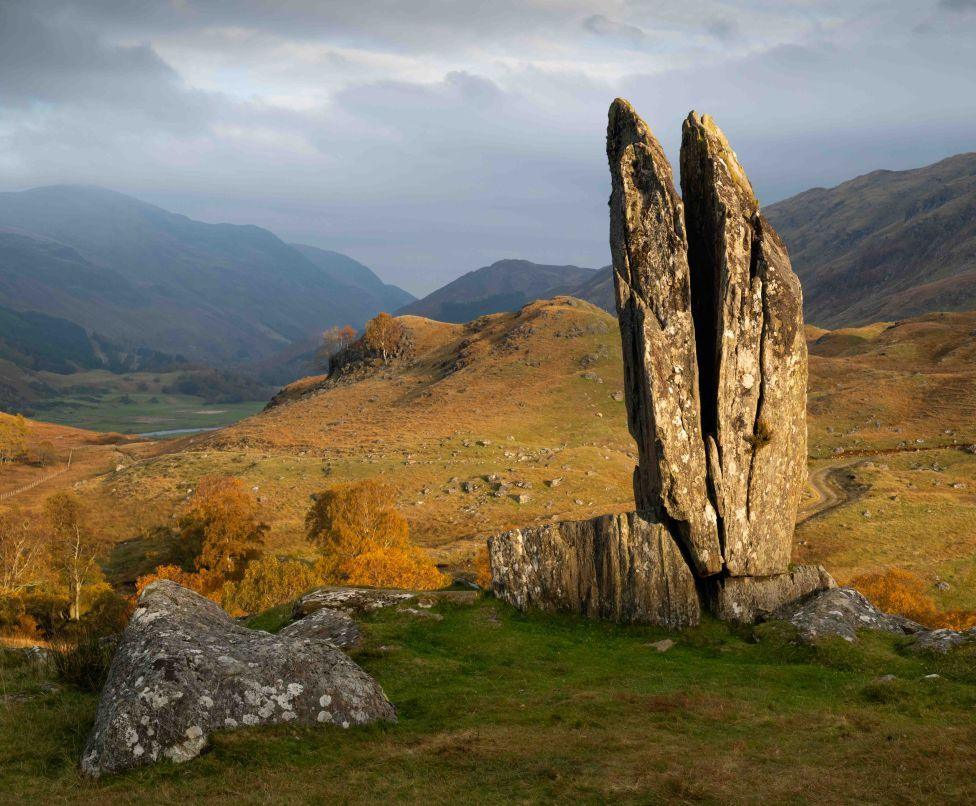 A large rock monument  on a sunny autumn day, surround by hills and mountains