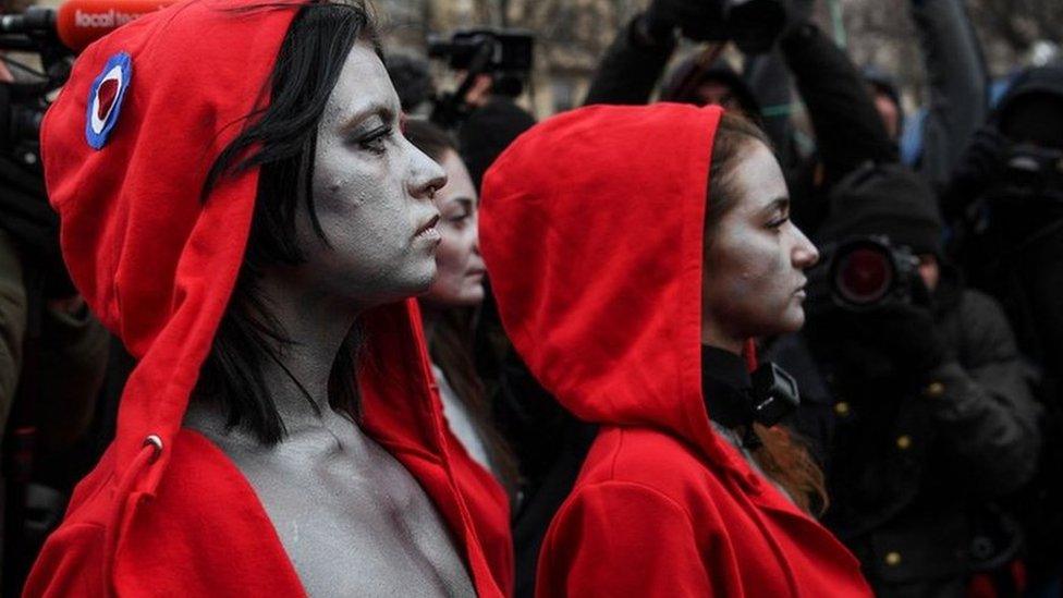 A group of women dressed as 'Marianne', a national symbol of the French Republic, perform and stand in front of the French Gendarmes in the Champs Elysees Avenue in Paris, on December 15, 2018