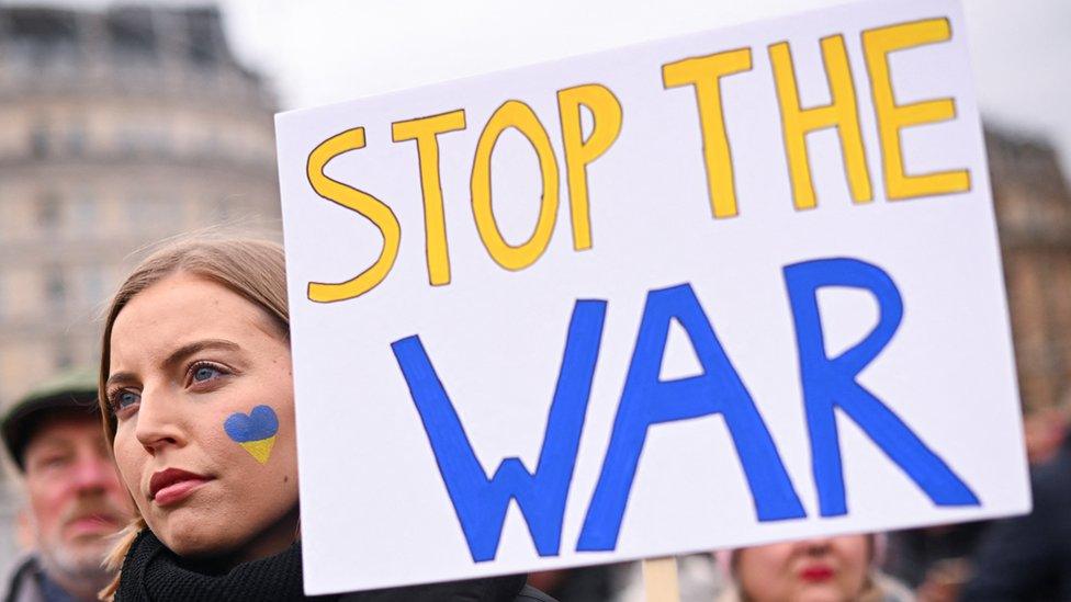 A woman holds a banner as she takes part in a protest against Russia's invasion of Ukraine