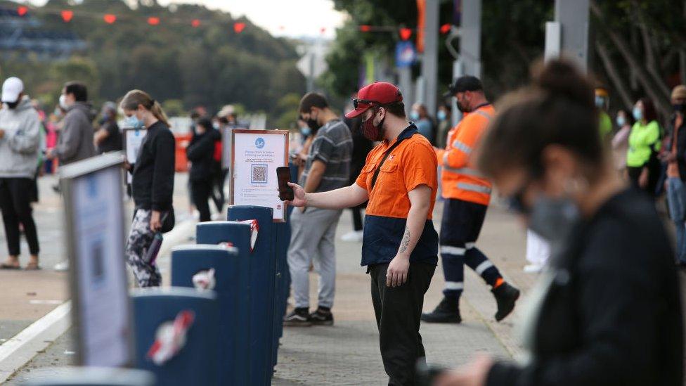 Queues of people use a QR code to check in at a Sydney stadium for their vaccination appointment