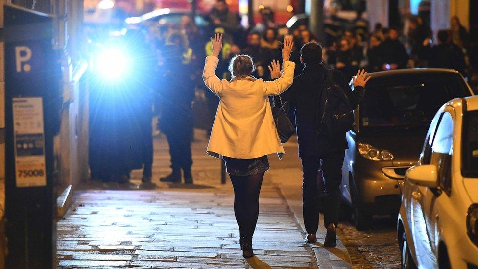 People hold their hands up as they walk towards police officers near the site of a shooting at the Champs Elysees in Paris, 20 April 2017