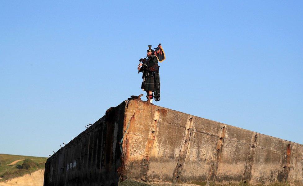 A lone piper plays on the Mulberry harbour at Arromanches in Normandy