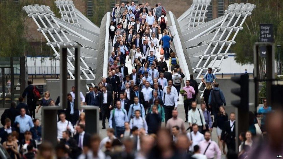 Commuters cross the river Thames on the Millennium footbridge as a tube strike hits the morning rush hour in the city of London