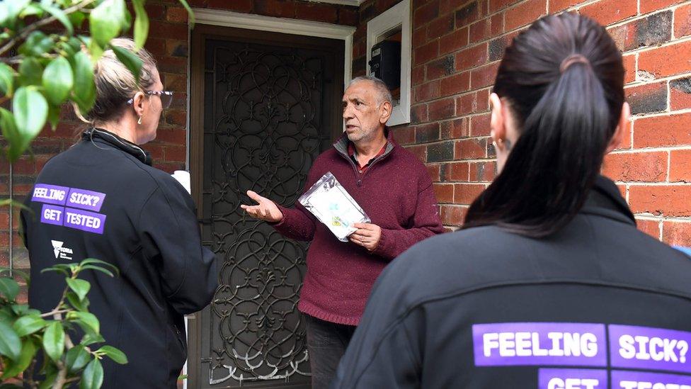 Health workers speak to a resident in an affected Melbourne area