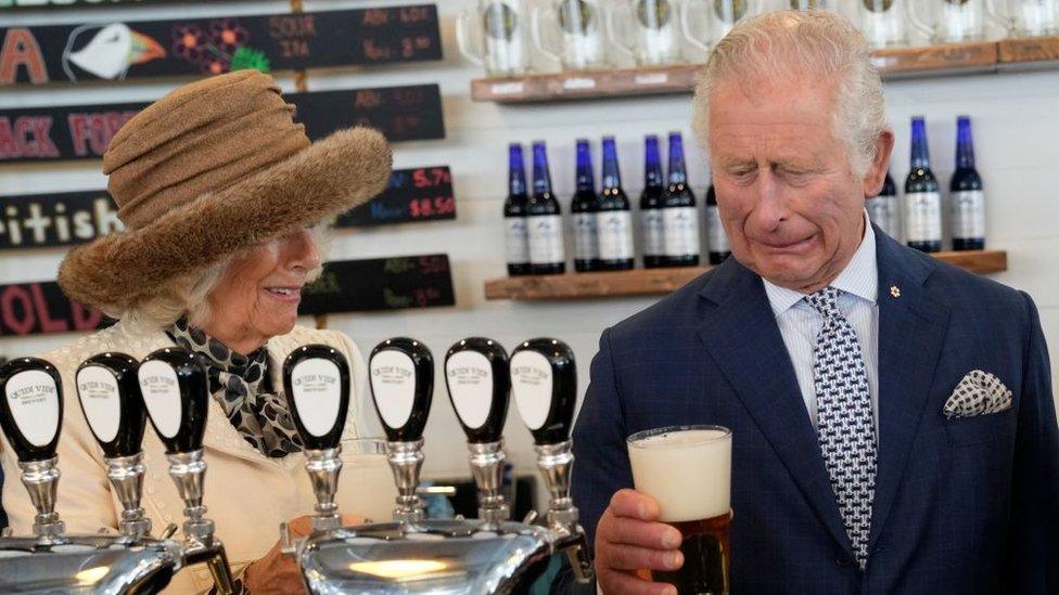 Camilla, Duchess of Cornwall, looks on as Prince Charles, Prince of Wales, reacts to a bad pour of beer he made at the Quidi Vidi Brewery, located in a fishing village in the east end of St Johns, Newfoundland and Labrador, on May 17, 2022