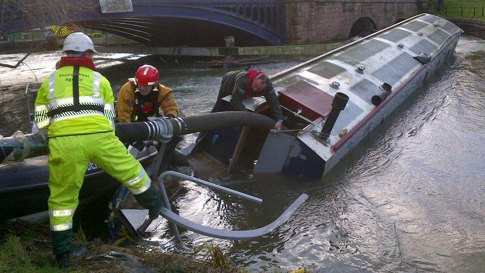 The Environment Agency and fire service personnel working to remove the boats