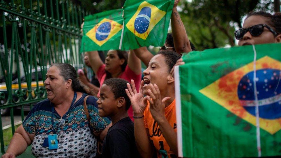 Relatives and friends of Evaldo dos Santos Rosa protest in Rio de Janeiro with red-stained Brazilian flags