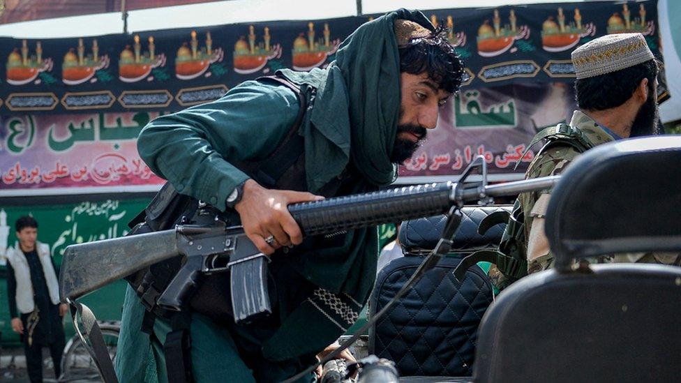 A Taliban fighter climbs up on a vehicle along a road in Kabul on 19 August 2021