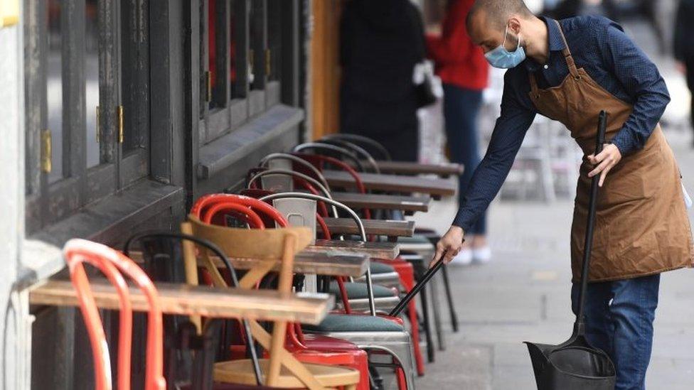 A man cleaning at a cafe in a mask