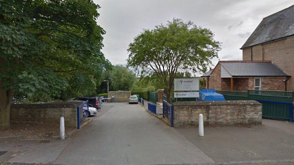 Entrance to school, showing school sign and car park