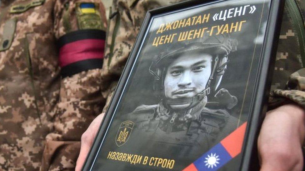 A soldier holds a photo of Tseng Sheng-guang at a memorial service