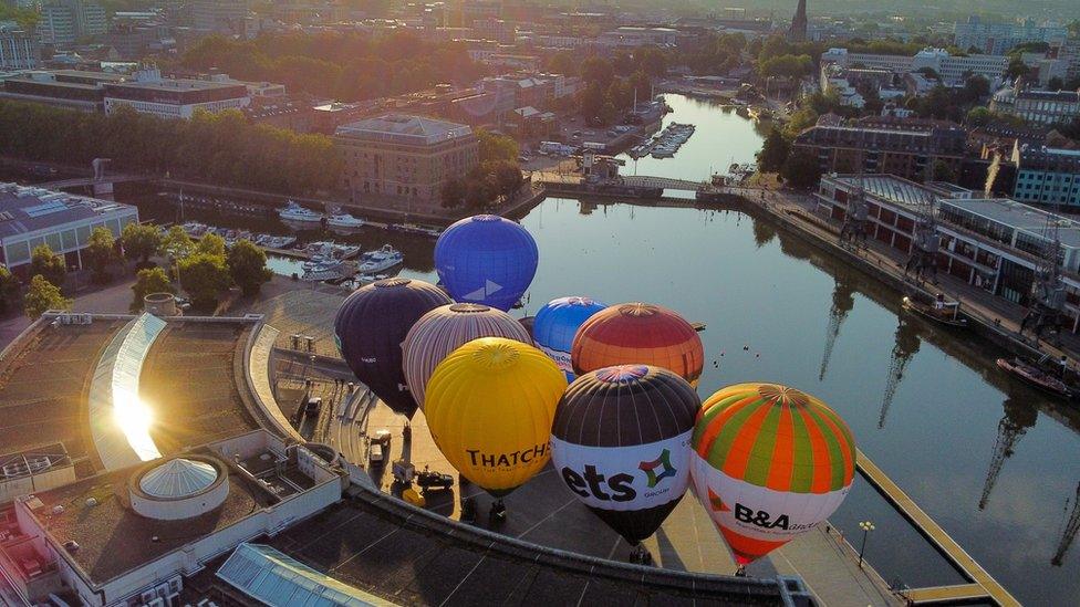 Hot air balloons inflate and tether from Bristol Harbourside