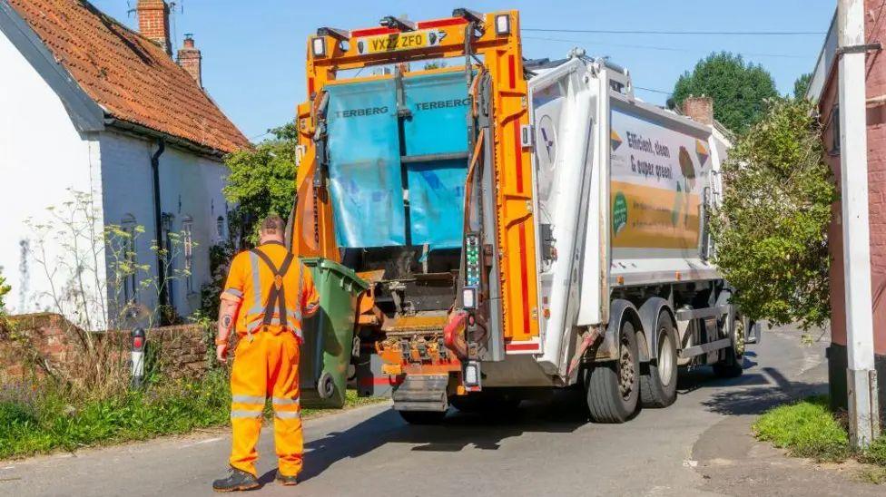 A binman emptying a bin into the back of a lorry