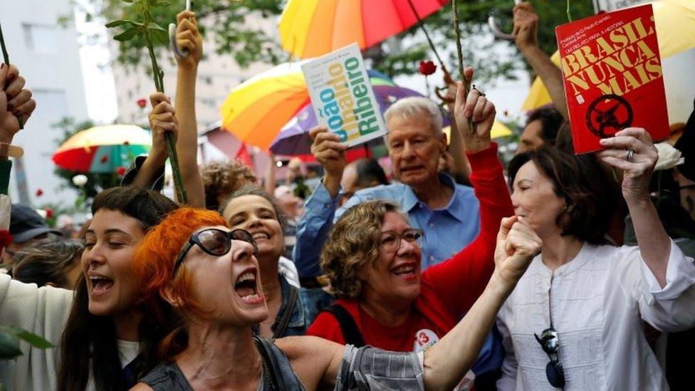 Supporters of Fernando Haddad hold up signs reading "Brazil, never again"