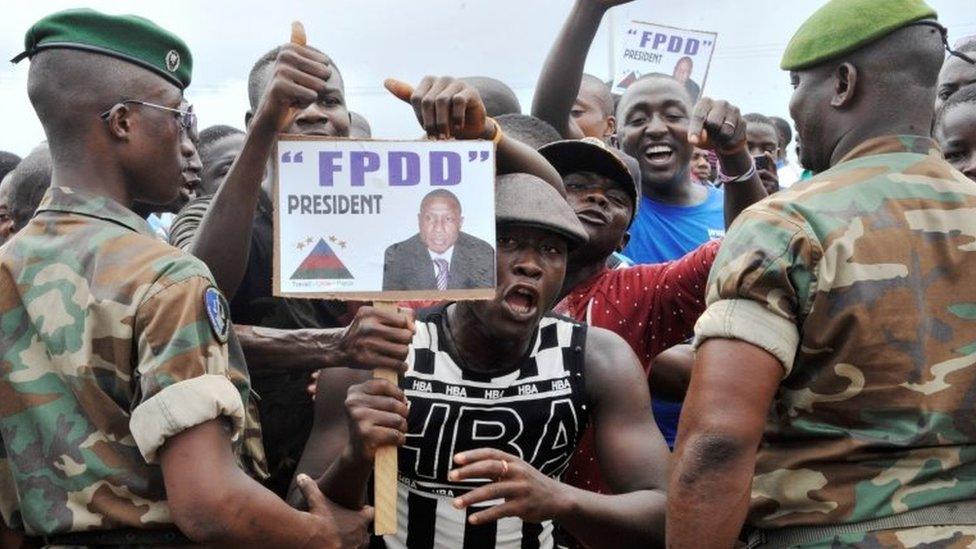 Supporters of Guinea's exiled former junta chief Moussa Dadis Camara demonstrate in front of soldiers, on 26 August 2015 at the airport in Conakry