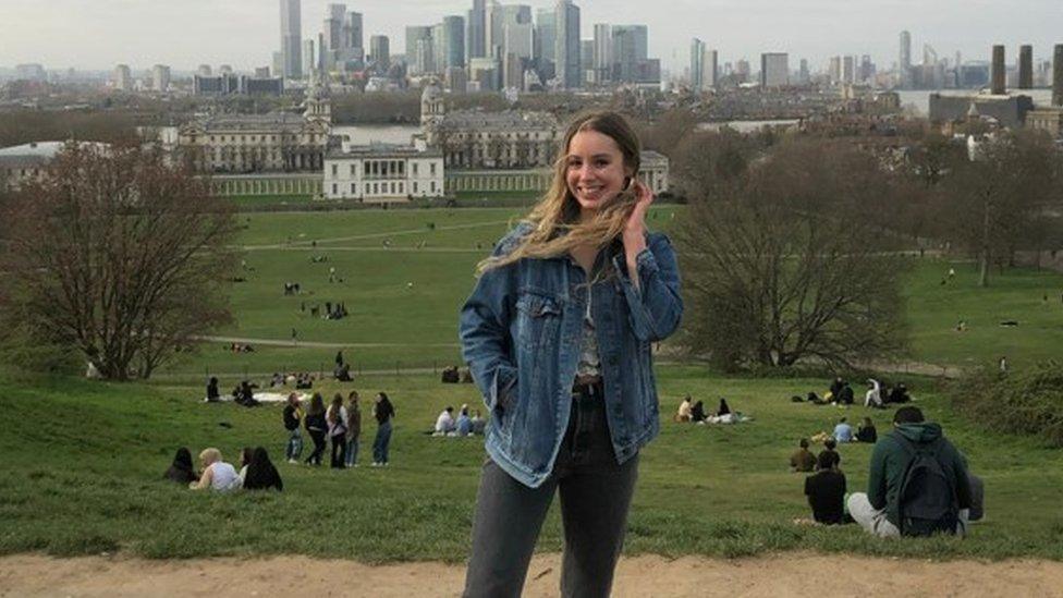 Ella Watson stands on a hill with the City of London behind her