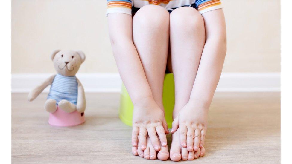 Boy sitting on a potty with his teddy bear next to him