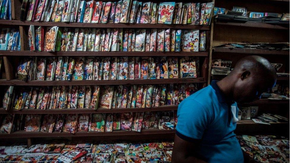 A man stands in a shop selling Nollywood films