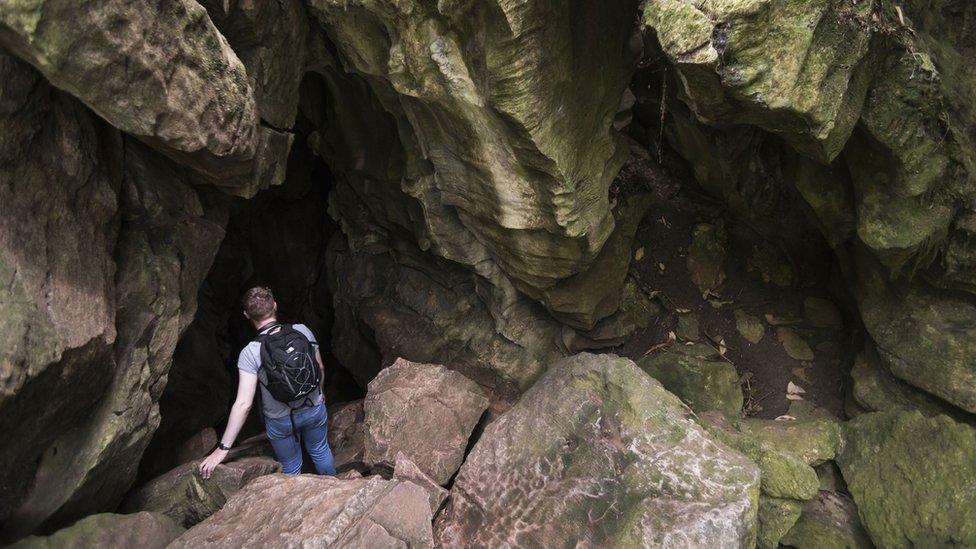 A tourist stands on the mouth of Abbey Caves