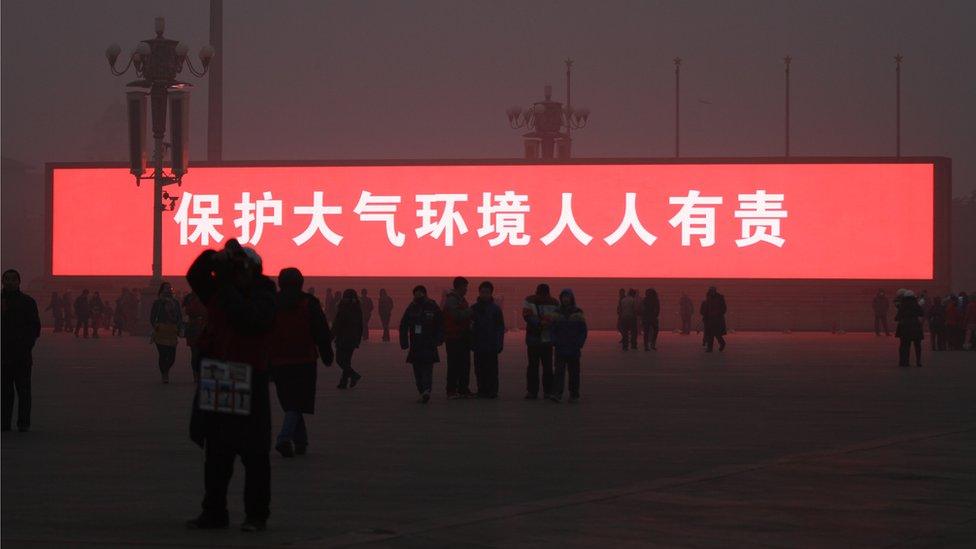 An LED screen reading "protecting the atmospheric environment is everyone's responsibility" on display in Tiananmen Square, Beijing, China, as it is shrouded in heavy smog. 16 January 2014.