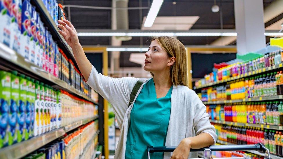 Woman in supermarket aisle looking at products