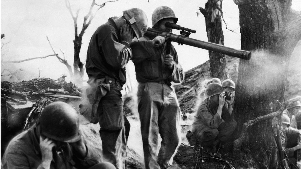 US infantrymen cover their ears as one fires a 75mm recoilless rifle, at the front lines in Korea.