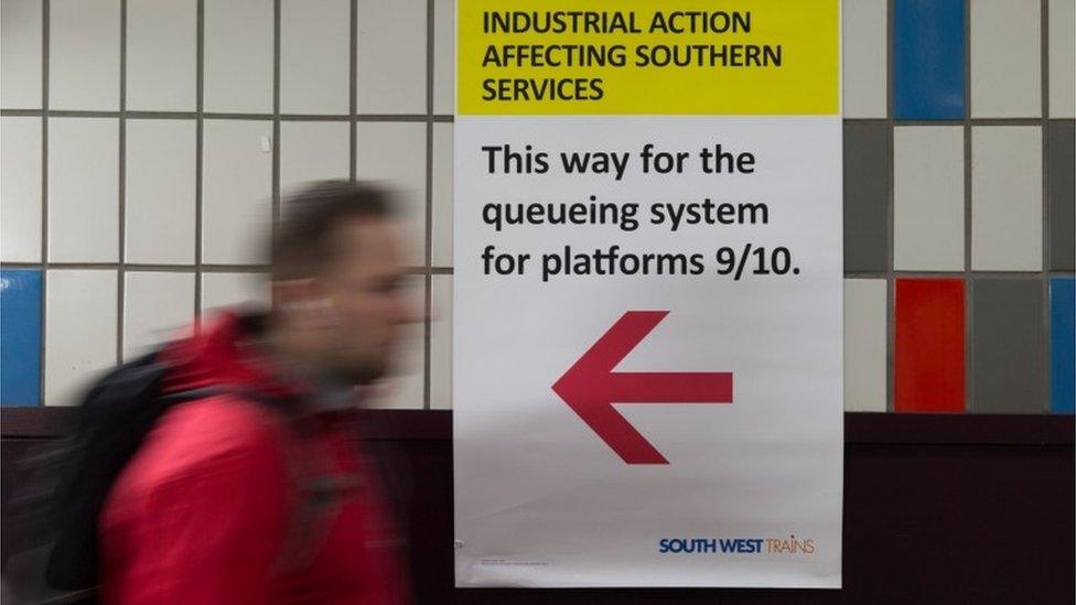 A passenger walks next to a information board pointing passengers toward a special queuing system