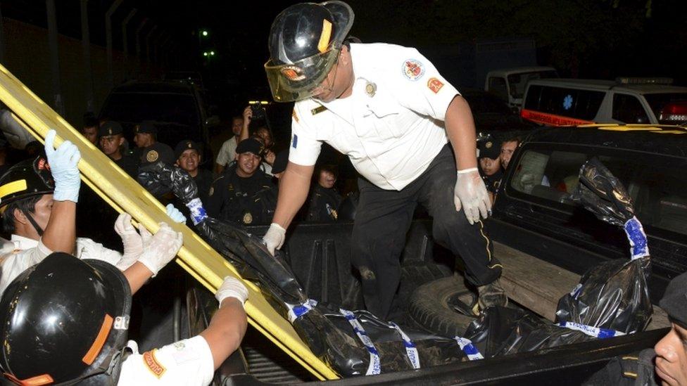 Fire-fighters deposit a body bag holding the body of a dead person on the loading area of a pick-up truck outside a prison in Escuintla, Guatemala, in this November 29, 2015 handout picture made available by Guatemala's Fire-fighters on November 30, 3015.